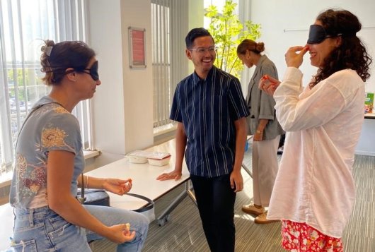 3 personen staan bij elkaar, waarvan 2 personen geblinddoekt zijn